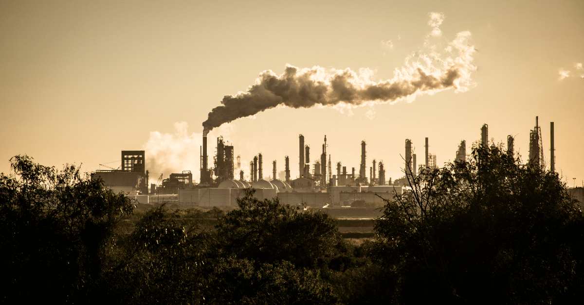 Billows of smoke rise over hazy industrial landscape